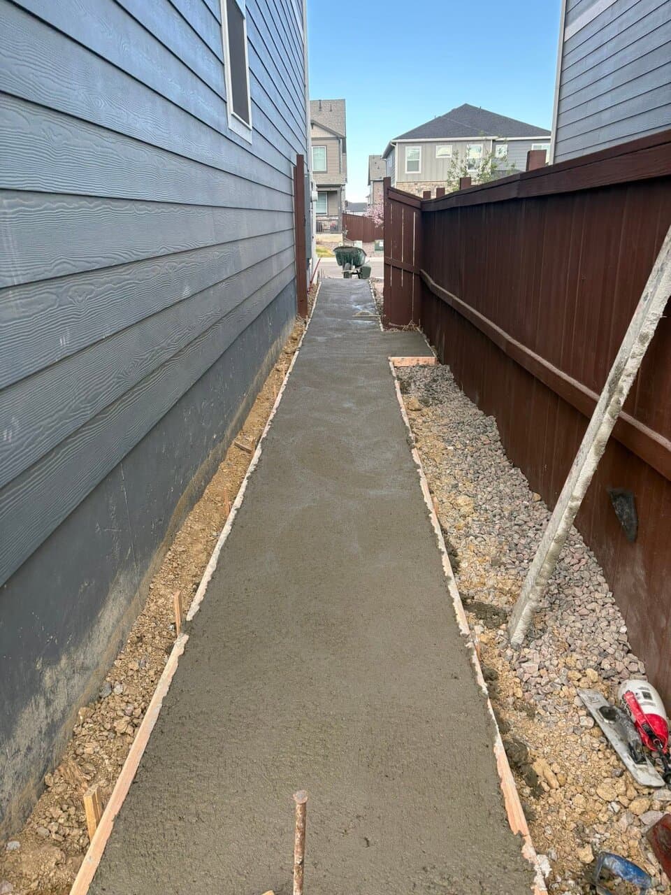 Narrow concrete pathway between fences in evening light