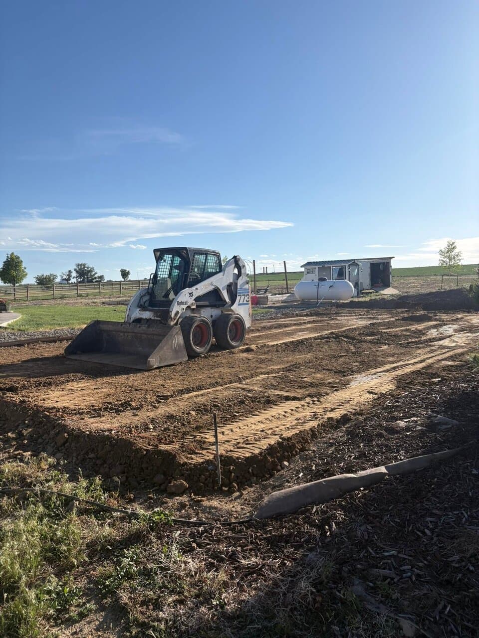 Skid-steer loader grading dirt at construction site