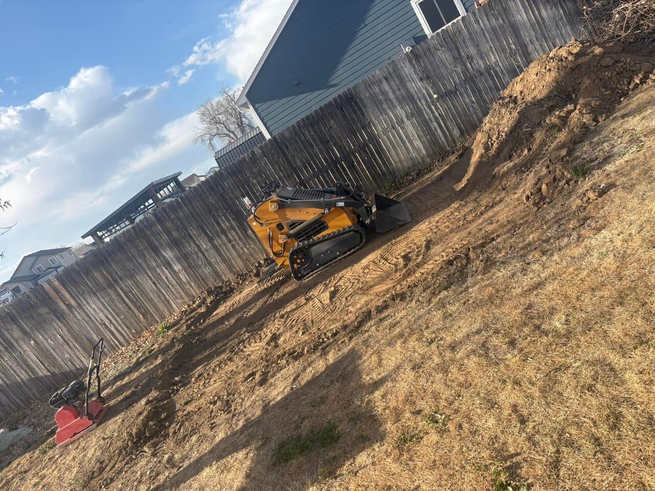 Yellow skid-steer loader positioned on a sloped dirt area